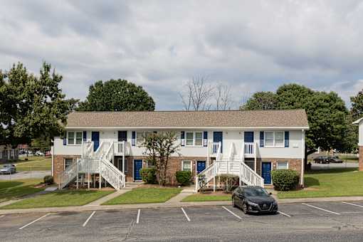 A two-story building with a car parked in front.