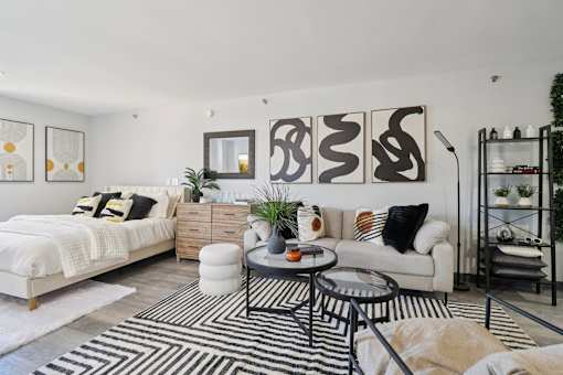 A modern living room with a white sofa, a black and white rug, and a wooden coffee table.