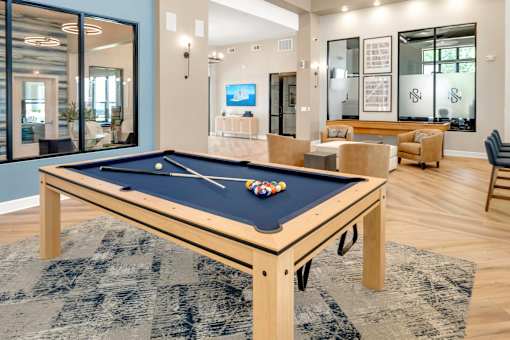 A pool table with a blue cloth and white balls is in the center of the room.