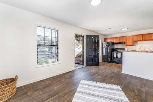 A kitchen with wooden floors and a black refrigerator.