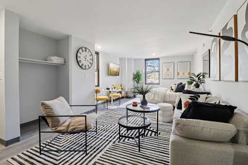 A living room with a black and white striped rug, a grey couch, a yellow chair, and a black coffee table.