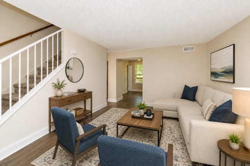 A living room with a white couch, blue chairs, and a wooden coffee table.