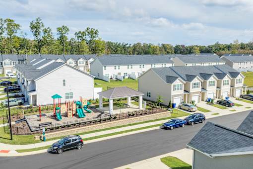 A suburban street with a playground and houses.