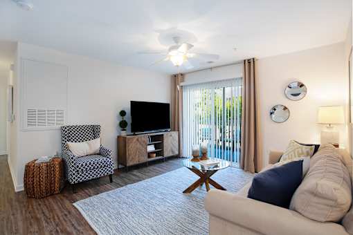 A living room with a chair, a sofa, a coffee table, and a television.