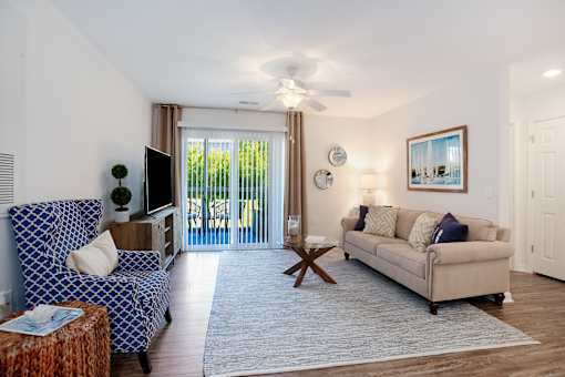 A living room with a blue patterned couch and a beige couch.