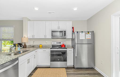 A kitchen with a refrigerator, microwave, and oven.