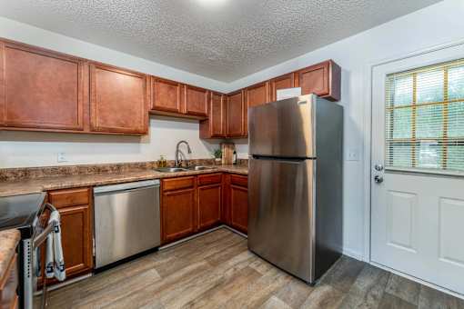 A kitchen with wooden cabinets and a stainless steel refrigerator.