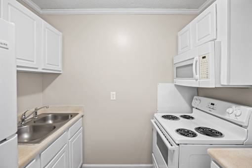 A white kitchen with a stove, sink, and microwave.