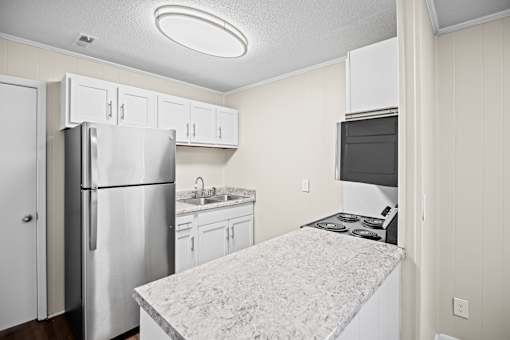A kitchen with a refrigerator, stove, and sink.