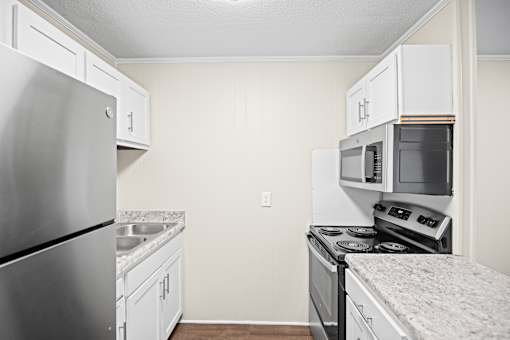 A kitchen with a stainless steel refrigerator, microwave, and oven.