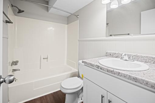 A white bathroom with a toilet, sink, and bathtub.