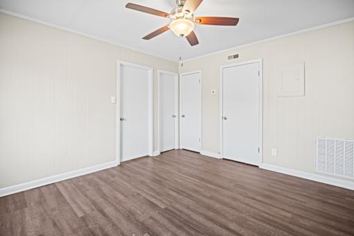 A room with a ceiling fan and three doors.