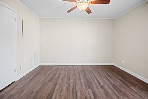A room with a ceiling fan and wooden flooring.