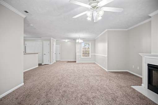 A room with a carpet floor and a ceiling fan.