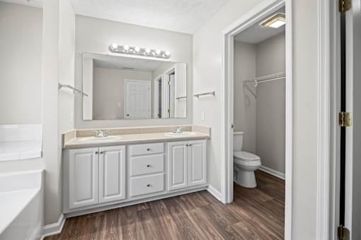 A white bathroom with a wooden floor and a white tub.