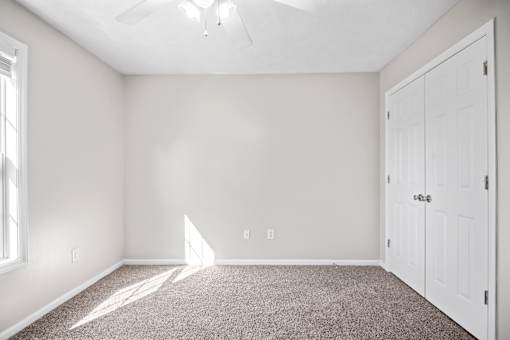 A room with a carpeted floor and a ceiling fan.