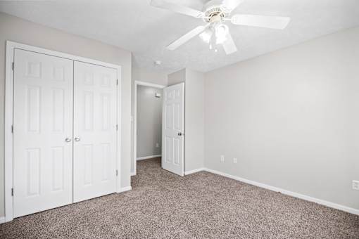 A room with a ceiling fan and carpeted floor.