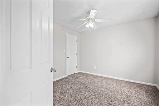A room with a ceiling fan and carpeted floor.