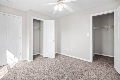 A room with a carpeted floor and a ceiling fan.