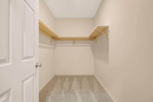 A white door is on the left of a hallway with a carpeted floor.