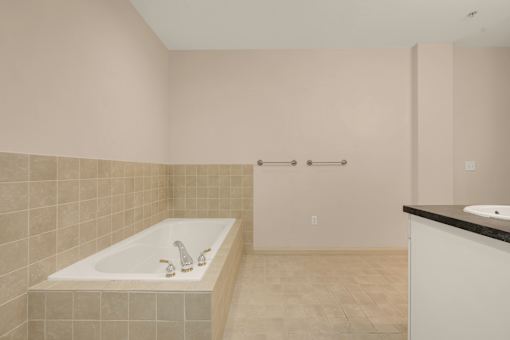 A bathroom with a white tub and a black counter.