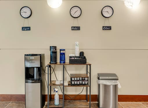 A room with a clock on the wall and a table with a bottle and a spray bottle on it.
