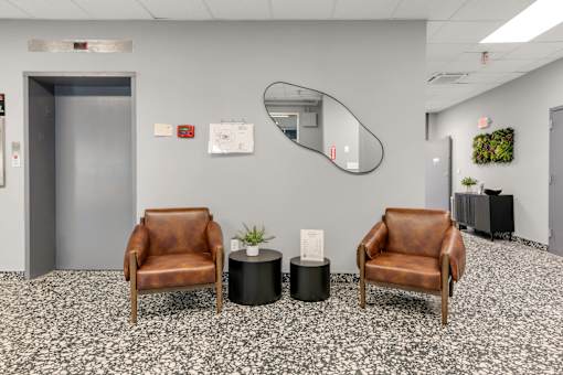 Two brown leather chairs are placed in front of a wall with a mirror.