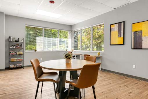 A conference room with a table, chairs, and pictures on the wall.