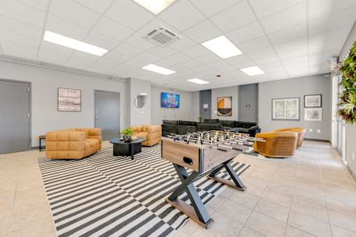 A room with a striped rug and a variety of seating options.