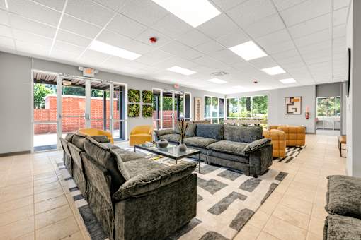 A spacious living room with grey couches and a black and white rug.