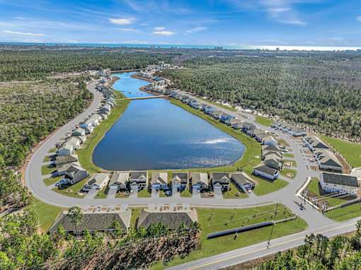 A bird's eye view of a residential area with a lake in the foreground.