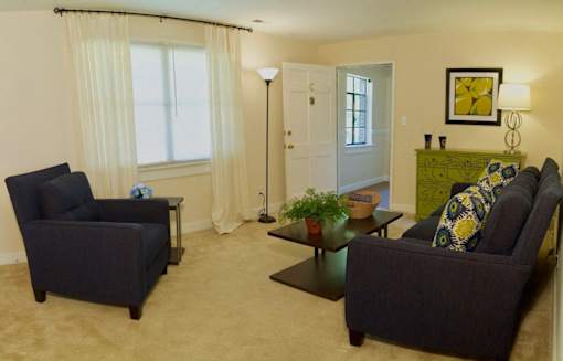 View of living room model with sofa, chair, coffee table and bookshelf