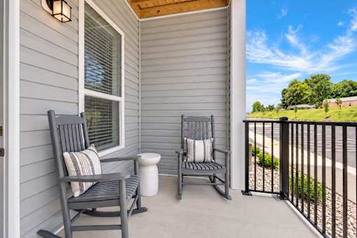 A porch with two chairs and a table.