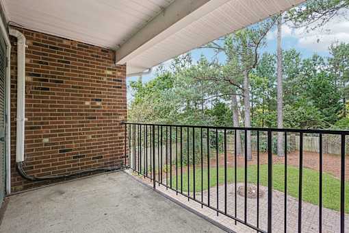 A balcony with a black railing and a brick wall.