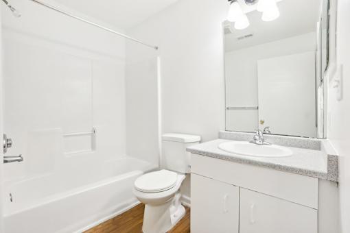 A white bathroom with a toilet, sink, and bathtub.