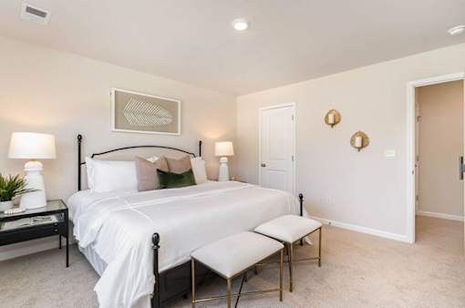 A bedroom with a bed, nightstand, and chair.