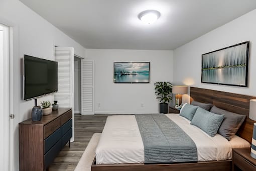 A bedroom with a large bed and a television on a cabinet.