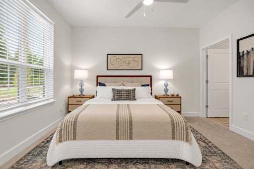 A bedroom with a large bed and two lamps on either side of the bed.