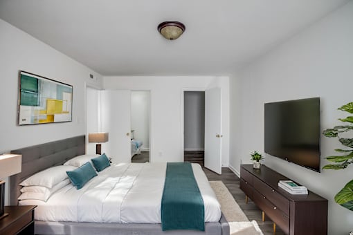 A bedroom with a large bed and a flat screen TV mounted on the wall.