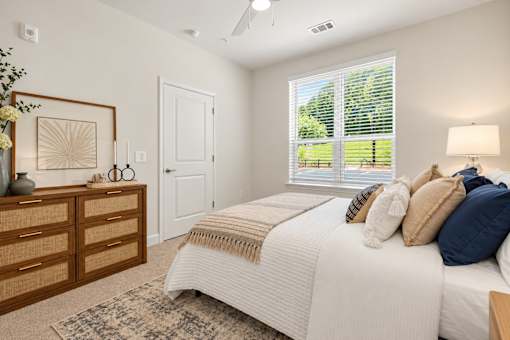 A bedroom with a large bed and a window overlooking a lawn.