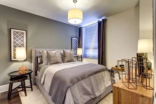 A bedroom with a large bed and a side table with a bottle on it.