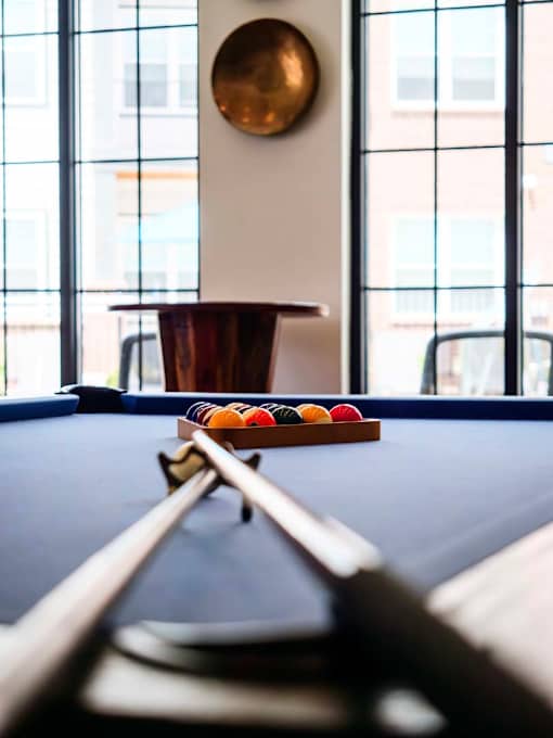 A pool table with a cue stick and balls.