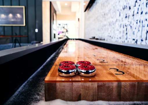 A wooden table with two red donuts and a number 3 on it.