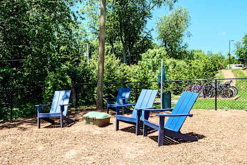 A group of blue chairs are arranged in a circle on a gravel area.