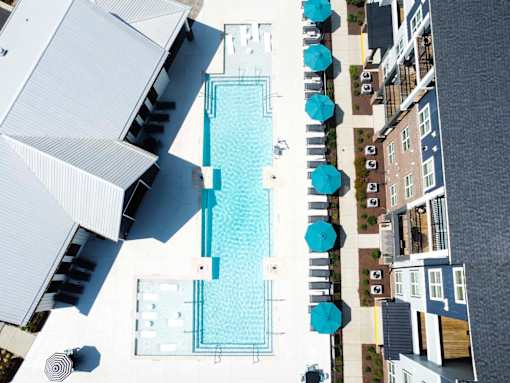 A swimming pool surrounded by blue umbrellas and white buildings.