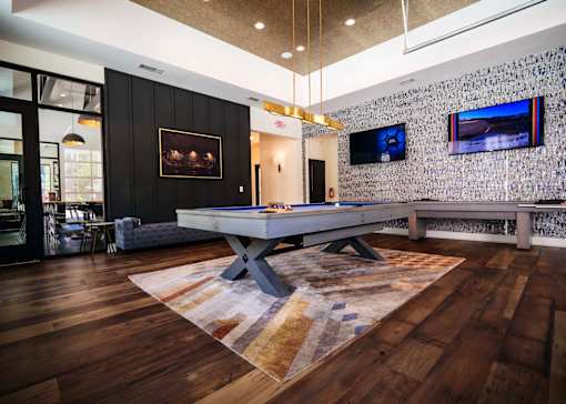 A room with a pool table and a tv on the wall.