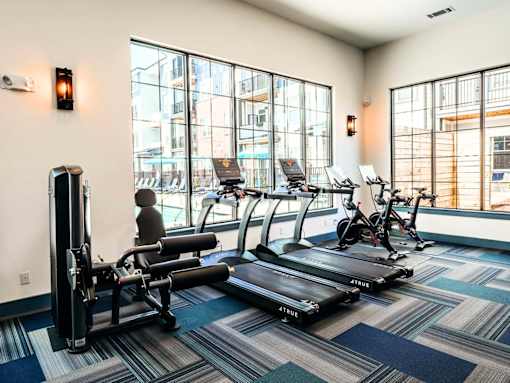 A gym with a row of treadmills and a row of stationary bikes.