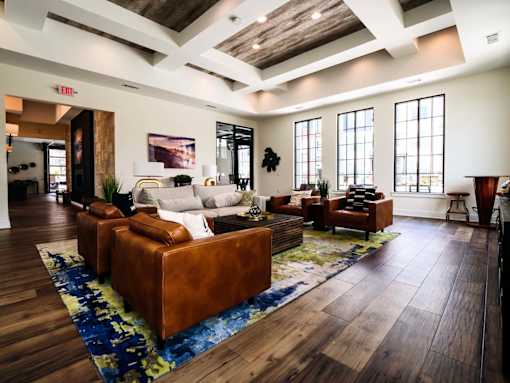 A living room with a brown leather couch and a blue rug.
