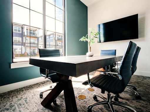 A black chair sits in front of a desk with a laptop on it.