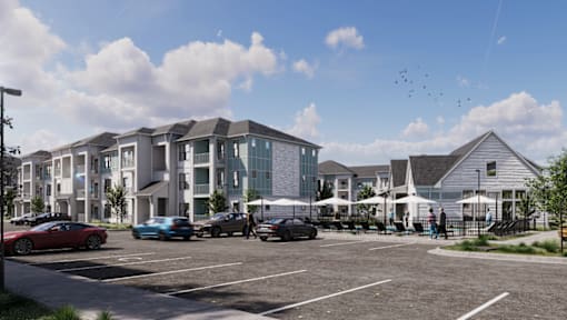 A modern building complex with a parking lot in front.